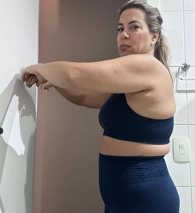 Luciana anos atrás, de lado, com roupa de ginástica