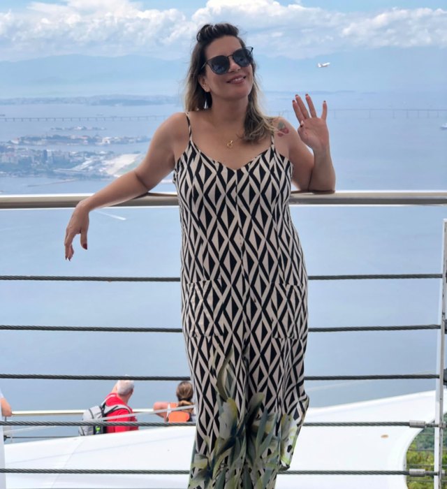 Luciana anos atrás, de vestido, na beira do mar