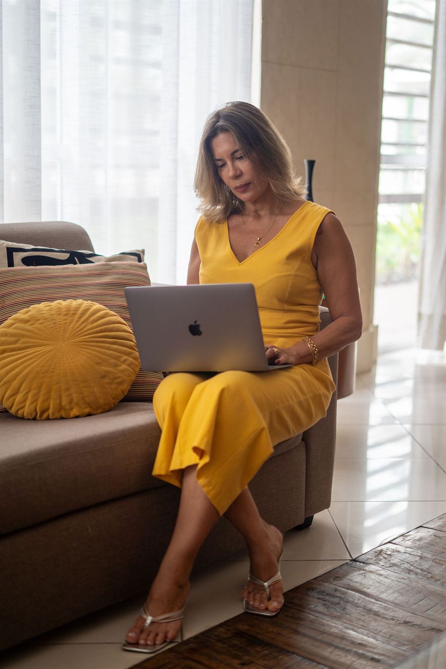 Nutri Luciana sentada no sofá, trabalhando no notebook